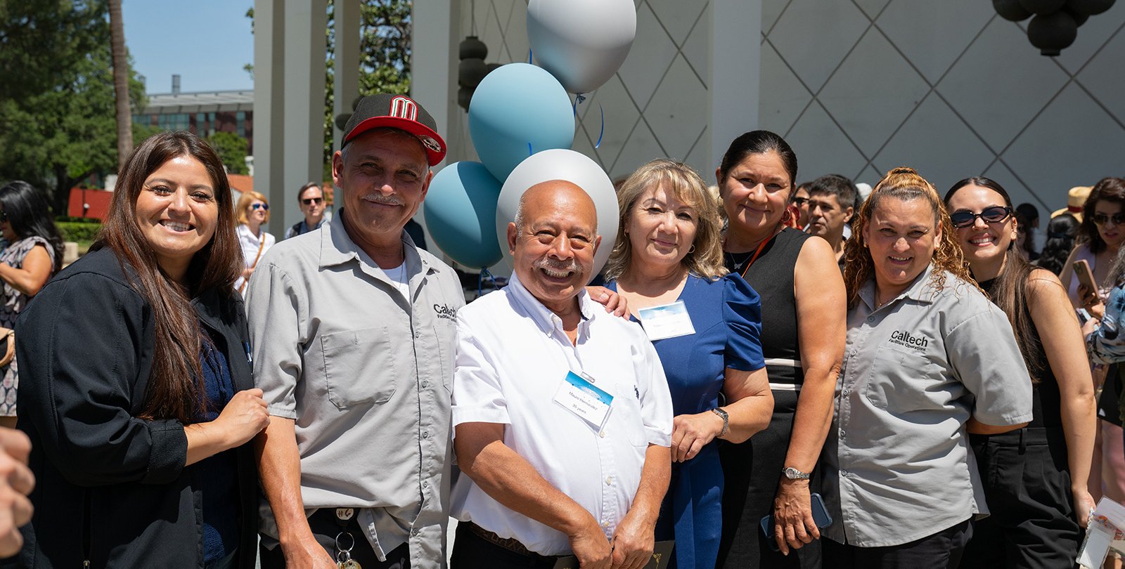 A line of people stand in the sunshine outside Beckman Auditorium following the 2025 Staff Service Awards