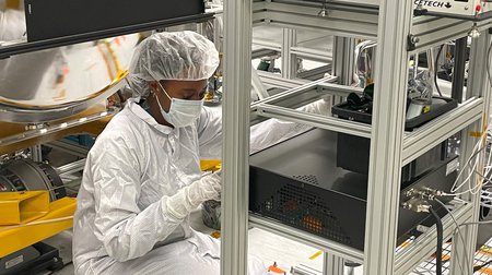 photo of Janelle Wellons working, wearing a clean room suit