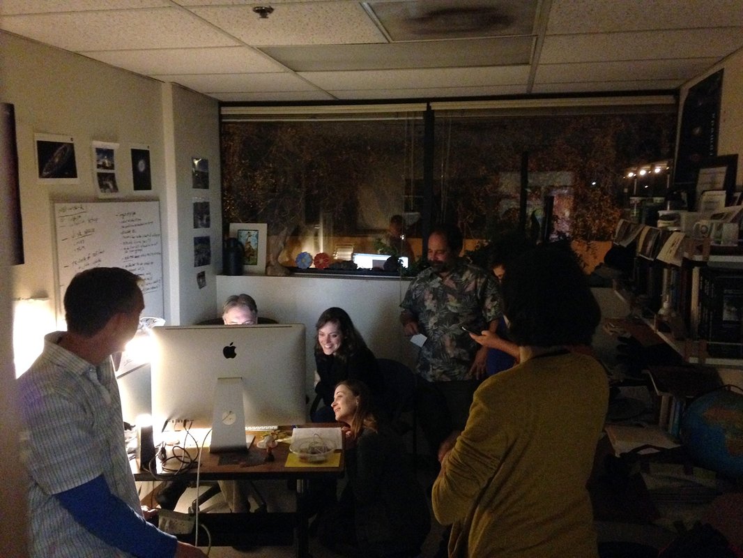people in a dark office crowded around a computer