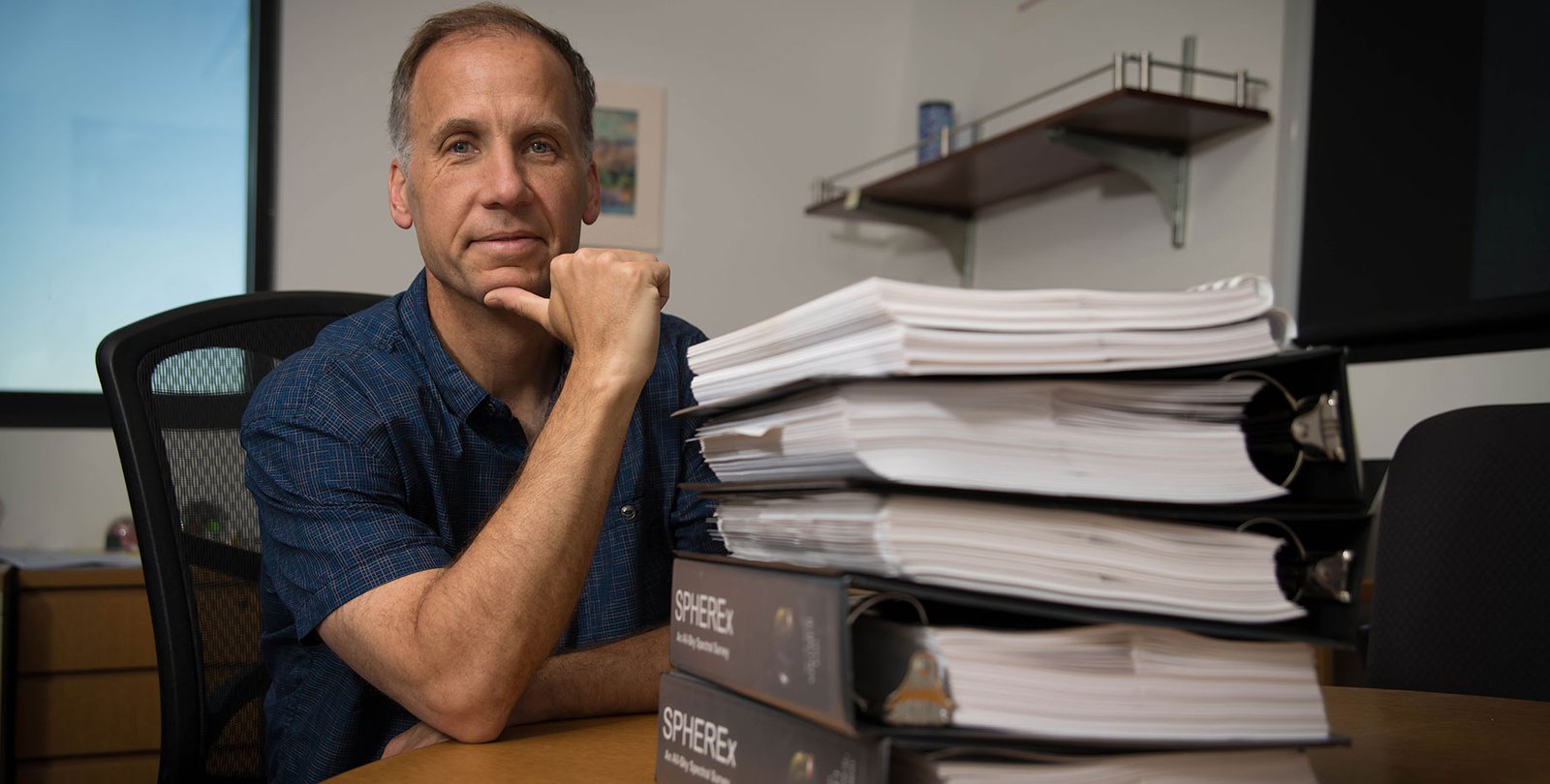Jamie Bock and a stack of SPHEREx mission proposals.