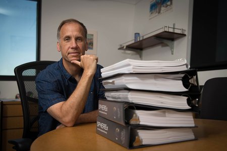 Jamie Bock and a stack of SPHEREx mission proposals.